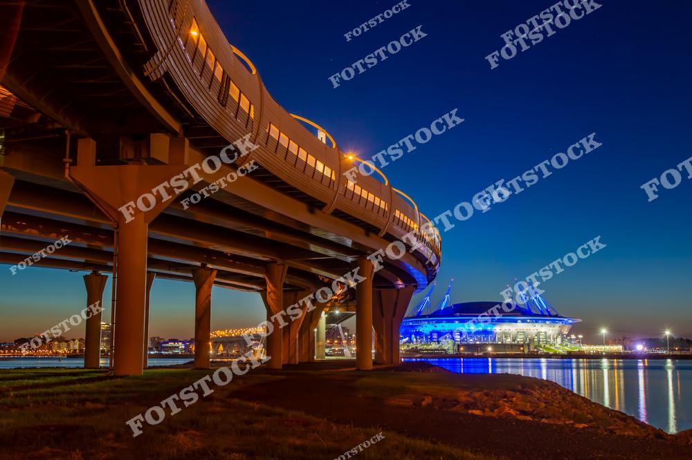 Фотография панорамы Санкт-Петербурга с видом на Крестовский остров, современные улицы и архитектуру центра города. На снимке сочетаются историческая атмосфера северной столицы России и новые строительные объекты, подчеркивающие развитие современного Петербурга. Широкие городские магистрали, здания и открытые пространства создают динамичный городской пейзаж, а панорамный ракурс позволяет увидеть масштаб и красоту города. Изображение отлично подходит для туристических публикаций, архитектурных проектов, интерьерных постеров, сувенирной продукции и коллекций фотографий Санкт-Петербурга.